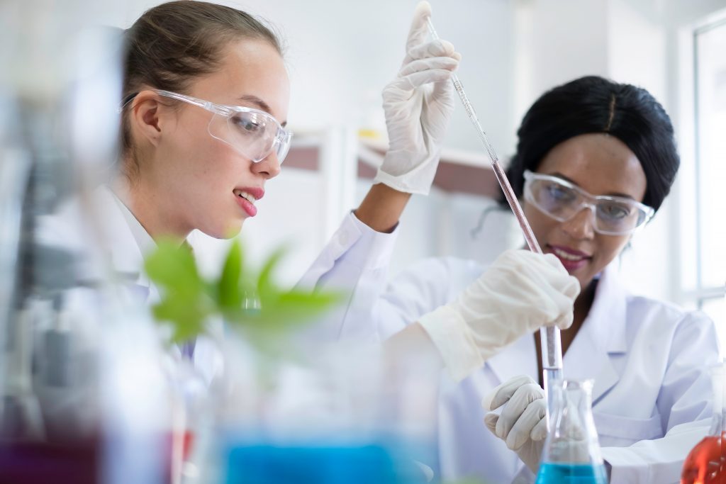 photo deux jeunes femmes chimistes prélèvent dans un tube avec une pipette laboratoire de recherche scientifique